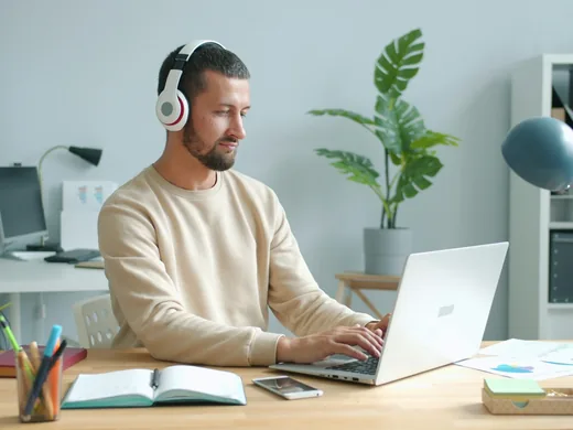 Uczestnik kursu w słuchawkach ogląda lekcję na laptopie